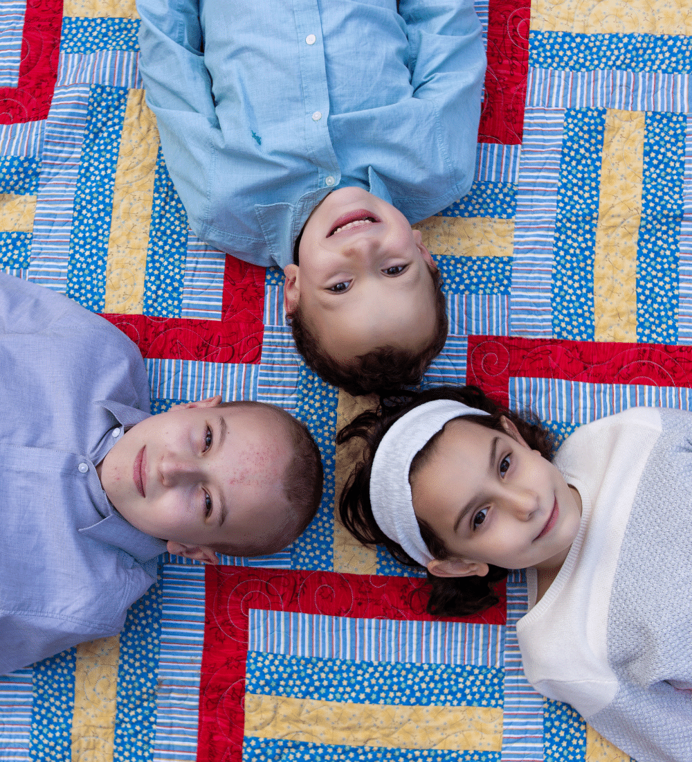 Three kids laying down smiling at camera